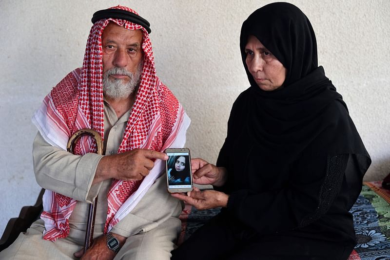 Palestinians Suleiman and Nazmiya Baraka show a picture of their slain daughter Istabraq Baraka, who was killed by her husband last year, on 27 June, 2022 in their home, in Khan Yunis in the southern Gaza Strip