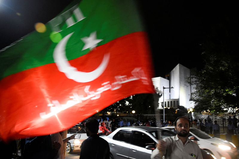 A supporter of the Pakistan Tehreek-e-Insaf (PTI) political party waves a flag as he celebrates after court ordered that backed by former Prime Minister Imran Khan, candidate for Punjab's chief minister, Chaudhry Parvez Elahi, to be installed as the province's premier, outside Supreme Court of Pakistan in Islamabad, Pakistan 26 July 2022.