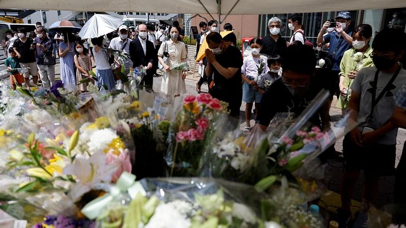 People queue up to offer flowers and pray at the site where late former Japanese Prime Minister Shinzo Abe was shot while campaigning for a parliamentary election, near Yamato-Saidaiji station in Nara, Japan, 9 July, 2022.