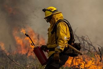 A firefighter uses a drip torch to light a backfire at the Oak Fire near Mariposa, California, on 24 July 24, 2022.