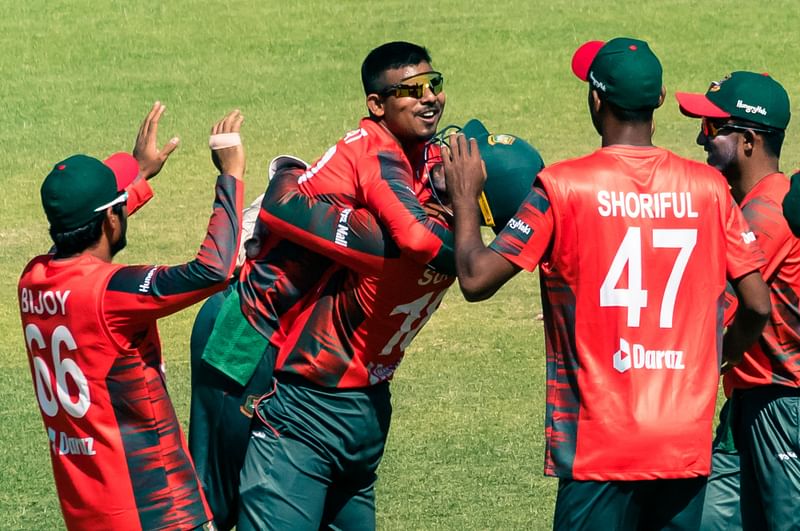 Bangladesh captain Nurul Hasan (c) lifts his bowler Musaddek Hossain (2nd L) on getting five wickets in action during the second T20 cricket match played between Bangladesh and hosts Zimbabwe, on 31 July, 2022 at the Harare Sports Club