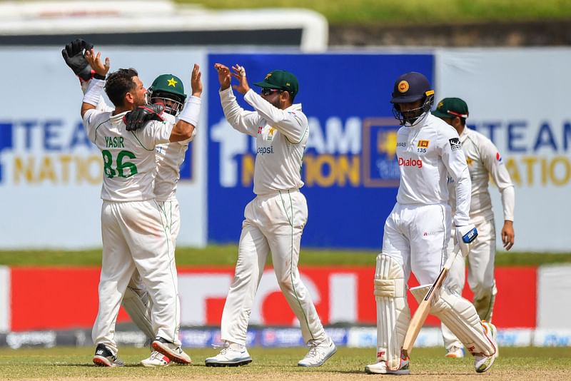 Pakistan's Yasir Shah (L) celebrates with teammates after taking the wicket of Sri Lanka's Dhananjaya de Silva (R) during the third day of play of the first Test between Sri Lanka and Pakistan at the Galle International Cricket Stadium in Galle on 18 July, 2022