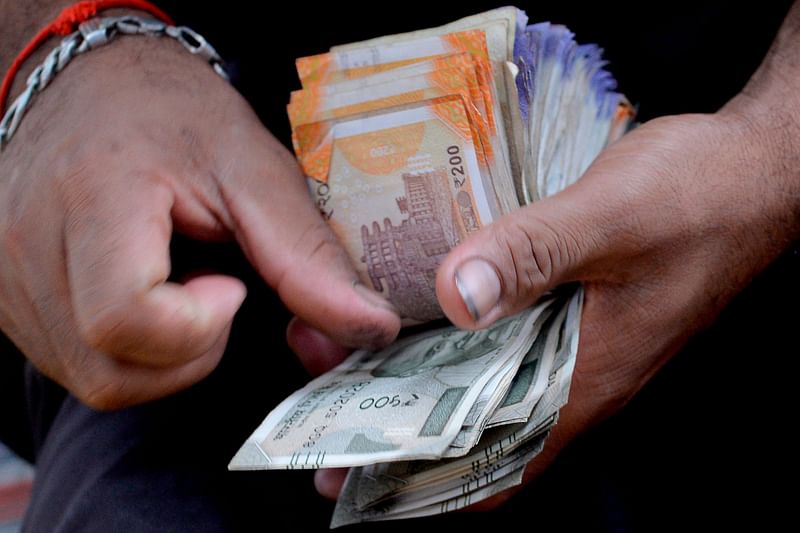 A fruit vendor counts a wad of Indian Rupee currency notes for payment at his roadside stall in Mumbai on 19 July, 2022