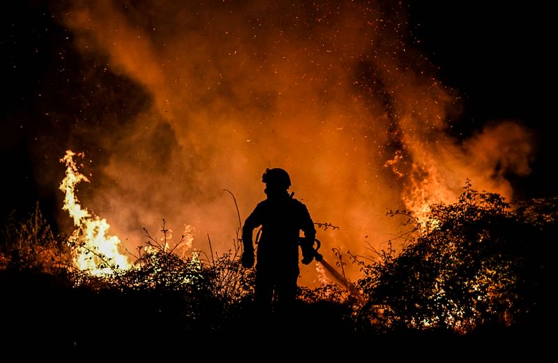 A firefighter tackles a forest fire around the village of Eiriz in Baiao, north of Portugal, on 15 July, 2022