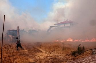 A person runs as wildfire approaches houses on Vatera coastal resort on the eastern island of Lesbos on 23 July, 2022. Residents were evacuated as the wildfire threatened properties.