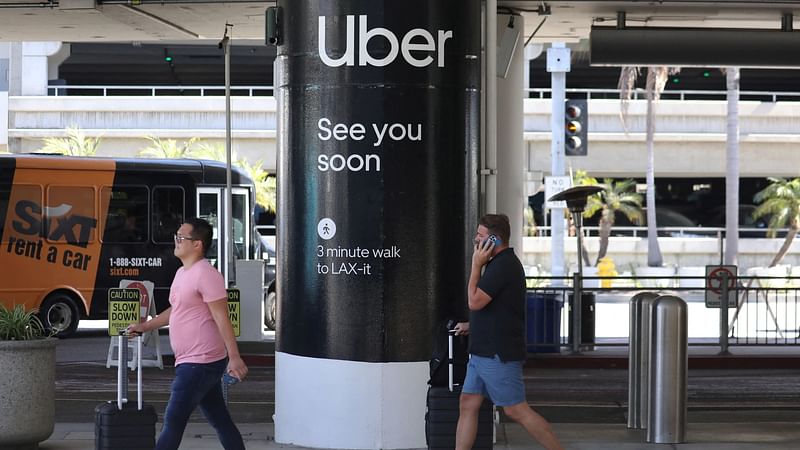 Passengers walk near Uber ride-share signage after arriving at Los Angeles International Airport (LAX) in Los Angeles, California, U.S. on 10 July 2022