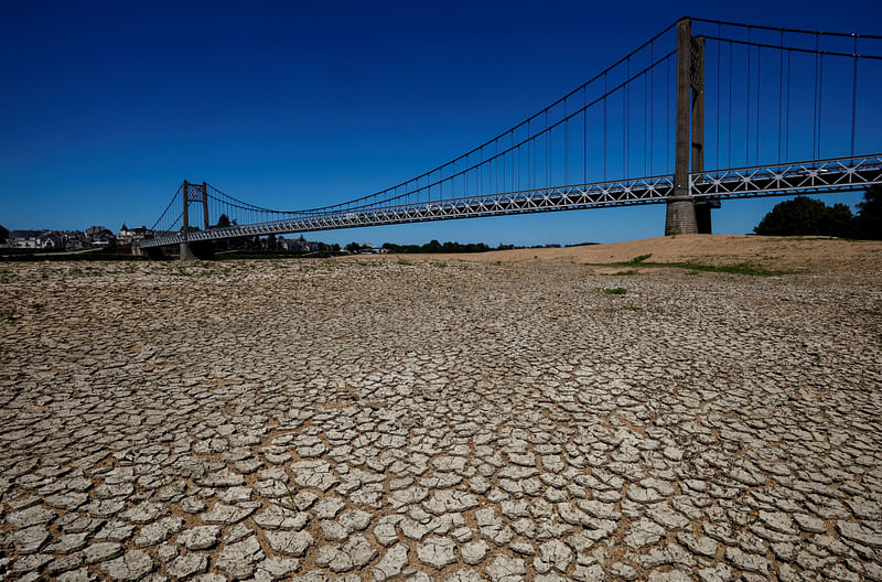 Cracked and dry earth is seen in the wide riverbed of the Loire River near the Anjou-Bretagne bridge as a heatwave hits Europe, in Ancenis-Saint-Gereon, France, 13 June, 2022