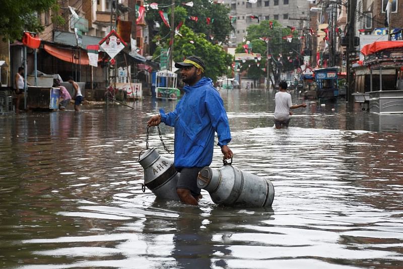 A man with milk-canisters walks along a flooded street, following rains during the monsoon season in Hyderabad, Pakistan on 24 August, 2022.