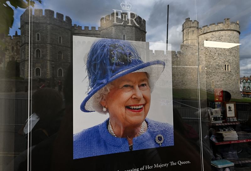 Windsor Castle is reflected in the window of a souvenir shop, displaying a tribute to the late Queen Elizabeth II, on September 16, 2022, following her death on 8 September.