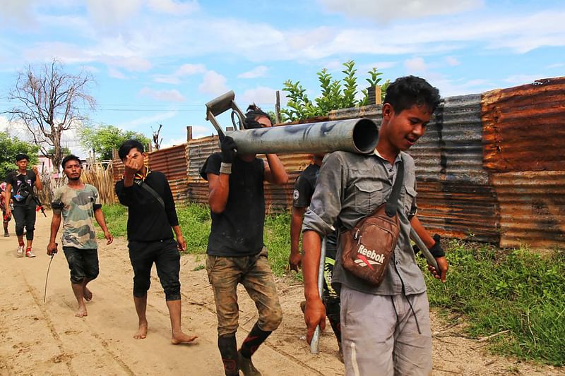 This photo taken on 10 August, 2022, shows anti-coup fighters walking with weapons in a township in Myanmar's northwestern Sagaing region