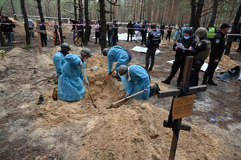 Forensic technicians dig a grave in a forest on the outskirts of Izyum, eastern Ukraine on 16 September, 2022. Ukraine said on 16 September, 2022 it had counted 450 graves at just one burial site near Izyum after recapturing the eastern city from the Russians