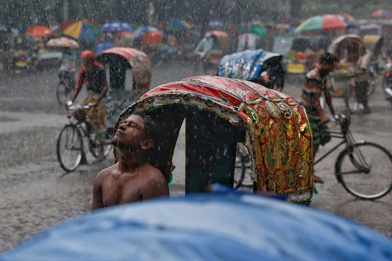 A rickshaw puller enjoys rain during monsoon in Dhaka, Bangladesh, 8 September 2022.