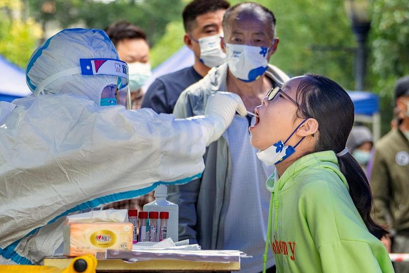 This photo taken on 17 September, 2022 shows a health worker taking a swab sample from a young resident to be tested for the Covid-19 coronavirus in Chengdu in China's southwestern Sichuan province