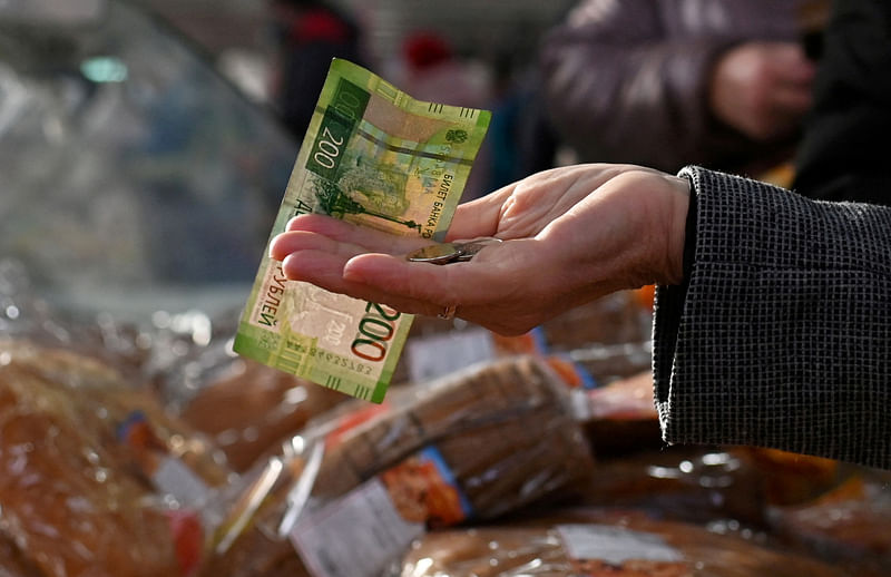 A customer hands over Russian rouble banknotes and coins to a vendor at a market in Omsk, Russia 29 October, 2021