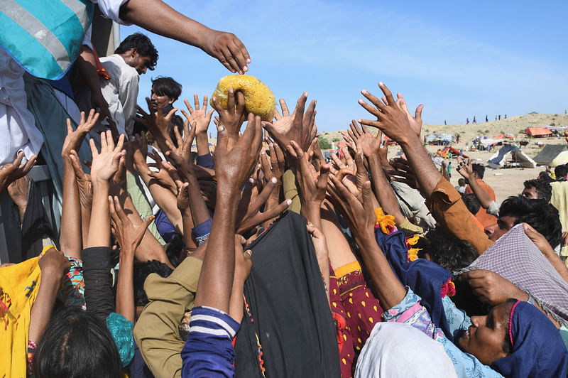 Flood victims reach out for food aid, while taking refuge on higher ground, following rains and floods during the monsoon season in Jhangara village in Sehwan, Pakistan on 1 September, 2022