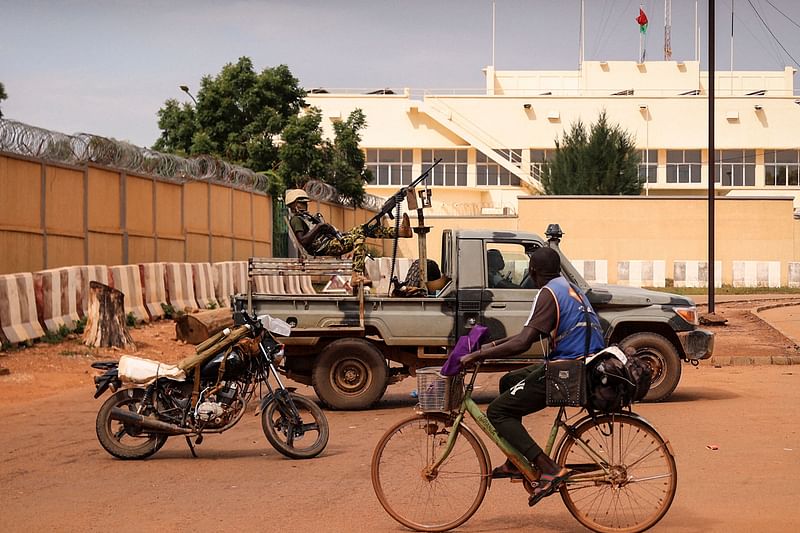 A man rides a bicycle past a soldier sitting on a pick-up truck as Burkina Faso soldiers are seen deployed in Ouagadougou on 30 September 2022.