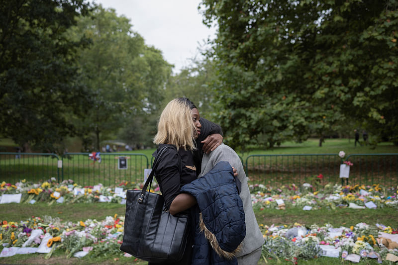 People react near floral tributes at the Green Park, near Buckingham Palace, following the death of Britain's Queen Elizabeth, in London, Britain on 13 September, 2022