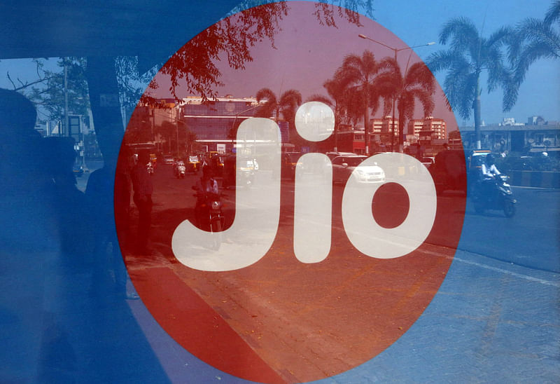 Commuters are reflected on an advertisement of Reliance Industries' Jio telecoms unit, at a bus stop in Mumbai, India 21 February, 2017