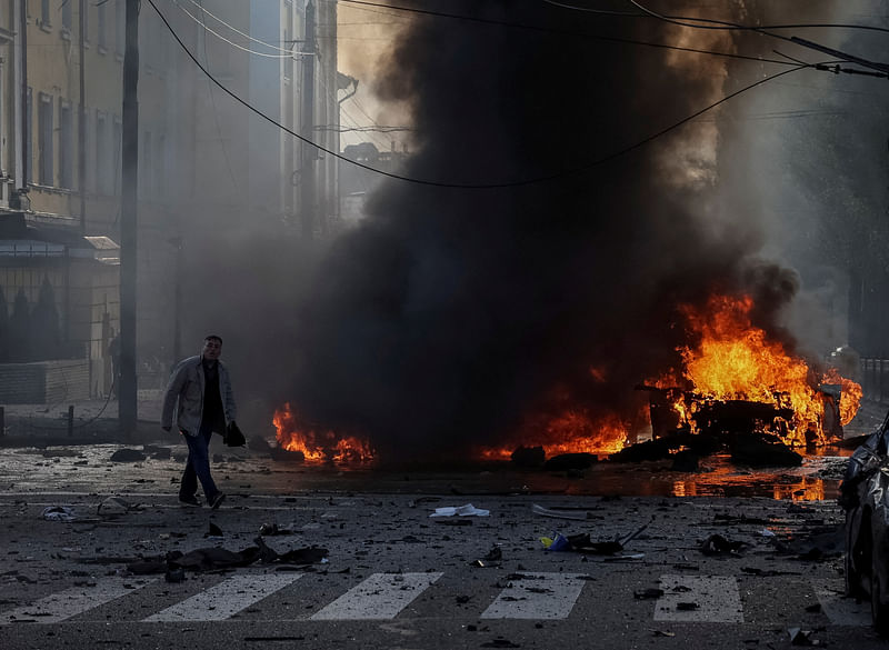 A driver walks near his burned car after Russian military strike, as Russia's invasion of Ukraine continues, in central Kyiv, Ukraine October 10, 2022