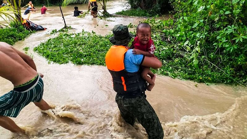 In this handout photo obtained from Regional Maritime Unit 12 - Sultan Kudarat Maritime Police Station Facebook page, rescuers help residents evacuate in Kalamansig, Sultan Kudarat on 28 October 2022, due to heavy rains resulting in floodings brought by Tropical Storm Nalgae.