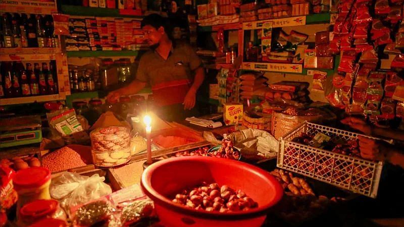 A shopkeeper  doing business in candlelight in Dhaka.