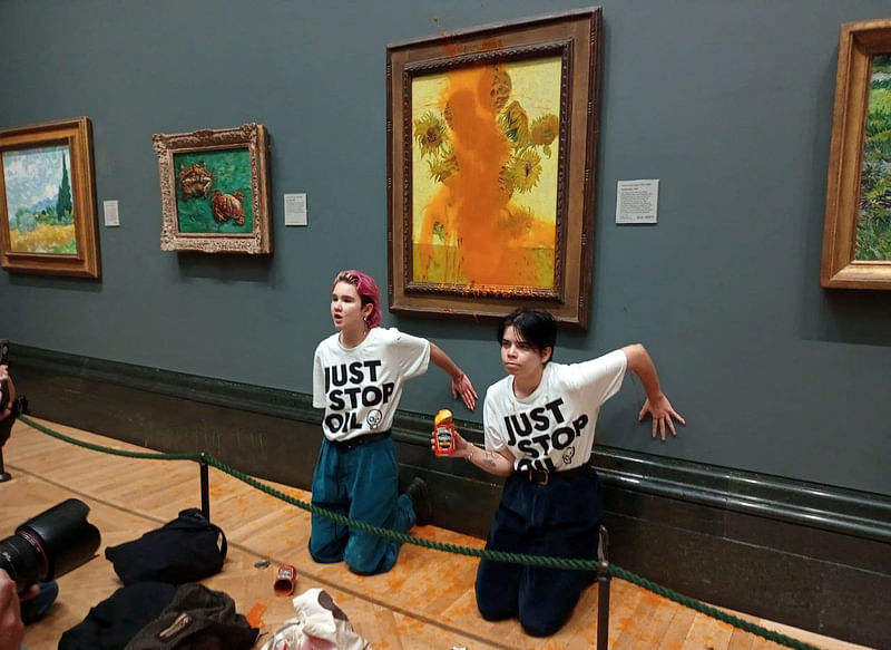 Activists of "Just Stop Oil" glue their hands to the wall after throwing soup at a van Gogh's painting "Sunflowers" at the National Gallery in London, Britain 14 October, 2022.