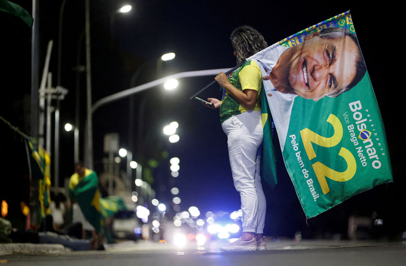 A supporter of Brazilian President Jair Bolsonaro looks at her mobile phone after polls were closed in Brazil's presidential election, in Brasilia, Brazil 2 October, 2022