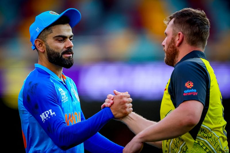 Australia's captain Aaron Finch (R) shakes hands with India's Virat Kohli after the Australia 2022 Twenty20 World Cup warm-up match between Australia and India at the Gabba in Brisbane on 17 October, 2022