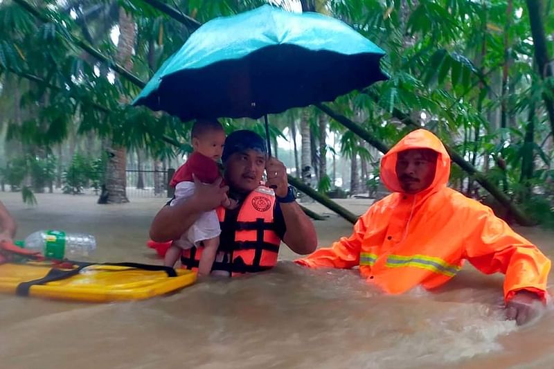 This handout photo taken on 28 October, 2022 and received from the Philippine Coast Guard on 29 October shows rescue workers evacuating people from a flooded area due to heavy rain brought by Tropical Storm Nalgae in Hilongos, Leyte province.