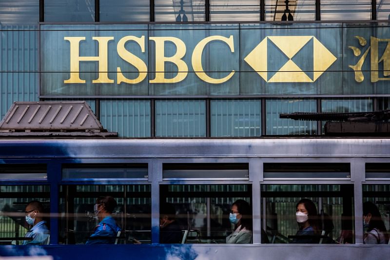 In this file photo taken on 25 October, 2021, people commute on a tram past the HSBC bank headquarters in Hong Kong. HSBC on 25 October, 2022 said pre-tax profit slipped in the third quarter of 2022 with the bank citing an impairment on the planned disposal of its retail banking operations in France.