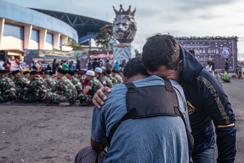 Indonesian army soldiers and civilians pay their respects for victims of the stampede at Kanjuruhan stadium in Malang, East Java on 4 October, 2022