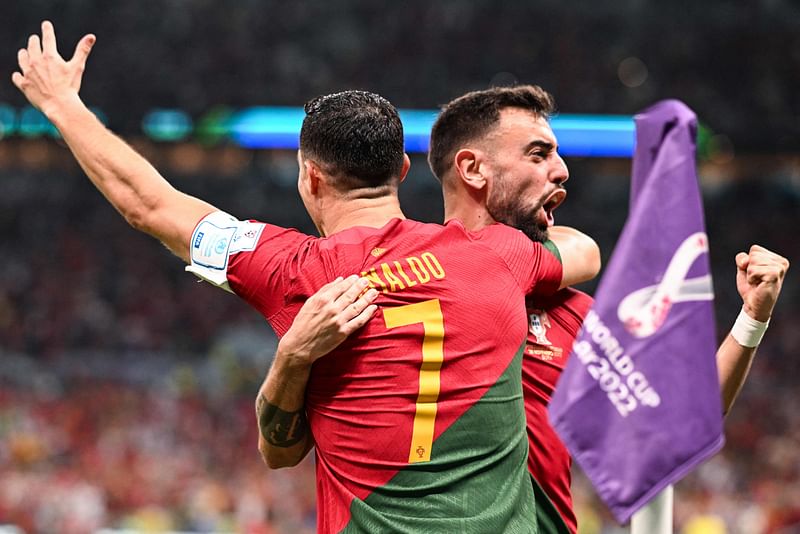 Portugal's forward Cristiano Ronaldo (L) celebrates scoring his team's first goal with Portugal's midfielder Bruno Fernandes during the Qatar 2022 World Cup Group H football match between Portugal and Uruguay