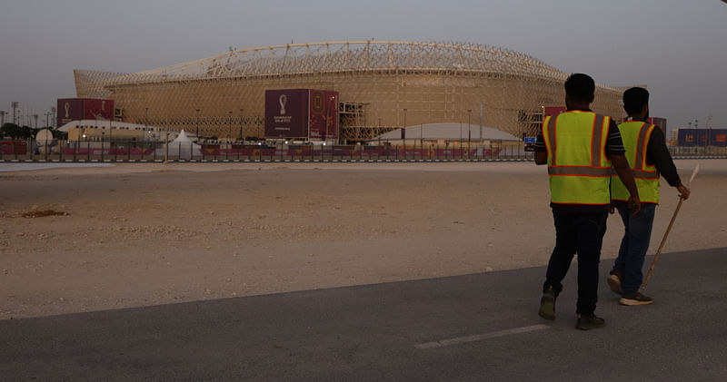 Workers walk past the Ahmad Bin Ali Stadium, one of the venues of the FIFA World Cup 2022