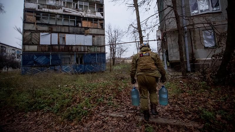 A police officer distributes water to local residents, amid Russia’s attack on Ukraine, in the town of Krasnohorivka, in Donetsk region, Ukraine, on 18 November, 2022