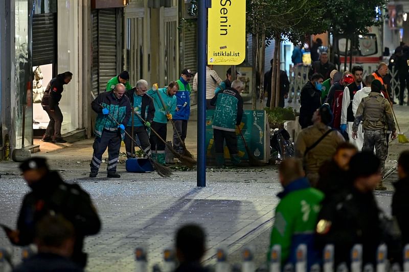 Municipal workers clean debris as Turkish policemen secure the area after a strong explosion of unknown origin shook the busy shopping street of Istiklal in Istanbul, on 13 November, 2022