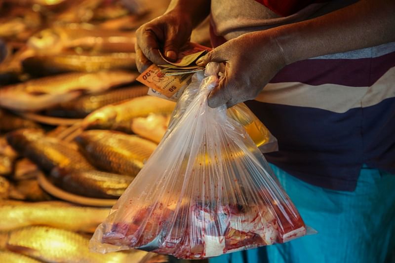 The prices of all commodities have skyrocketed due to the impact of rising inflation. A man counts his cash after purchasing a half litre palm oil and a kilogram catfish at Tk 70 and Tk 150 respectively. The picture was taken from Naya Bazar in Dhaka on 24 November.