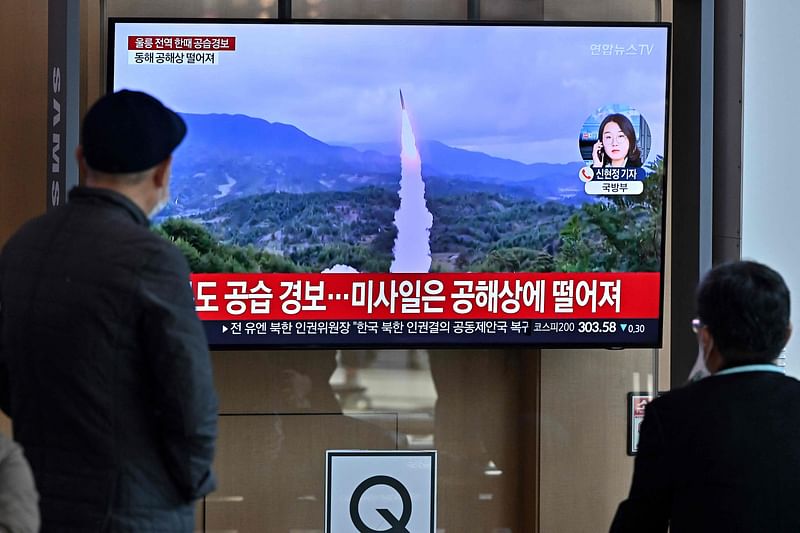 A man watches a television screen showing a news broadcast with file footage of a North Korean missile test, at a railway station in Seoul on 2 November, 2022