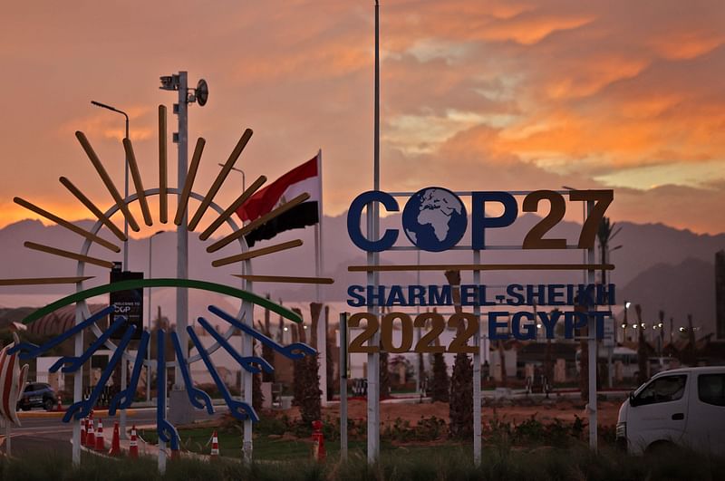 The sun sets behind the sign showing the logo of the COP27 climate conference at the Sharm el-Sheikh International Convention Centre, in Egypt's Red Sea resort city of the same name, on 14 Novmeber, 2022.