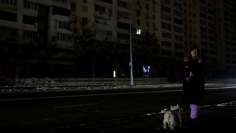 A woman with a dog waits for a bus in a street without electricity after critical civil infrastructure was hit by Russian missile attacks, amid Russia’s invasion of Ukraine, in Kyiv, Ukraine on 23 November, 2022