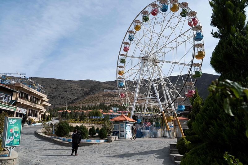 This photograph taken on 9 November, 2022, shows Taliban guards standing next to a ferry wheel ride at the Habibullah Zazai Park on the outskirts of Kabul