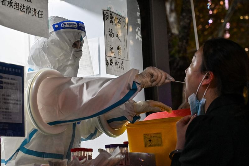 A health worker takes a swab sample from a woman to test for the Covid-19 coronavirus in the Jing'an district in Shanghai on 28 November, 2022