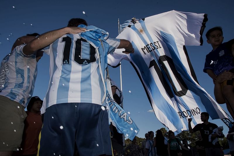 Fans look at a giant jersey of Argentine forward Lionel Messi displayed in Rosario, Argentina, on 15 December, 2022, on the eve of the Qatar 2022 World Cup final football match between Argentina and France