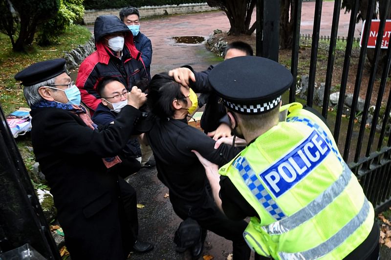 A file handout from The Chaser News taken on 16 October, 2022 and released to AFP on 17 October shows an incident involving a scuffle between a Hong Kong pro-democracy protester (C) and Chinese consulate staff, as a British police officer attempts to intervene, during a demonstration outside the consulate in Manchester