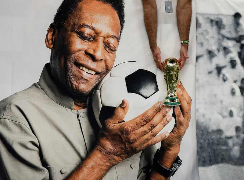 Brazil fan holds a replica World Cup trophy in front of a banner of former Brazil player Pele before the Cameroon v Brazil match at Lusail Stadium, Lusail, Qatar, 2 December 2022.