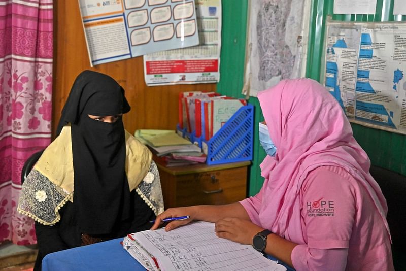 In this picture taken on 11 August, 2022, a health worker (R) speaks with a Rohingya refugee in a maternity ward of a medical centre in Kutupalong refugee camp in Ukhiya. Roughly two-thirds of Rohingya couples are now using some form of birth control -- up from virtually none five years ago, according to figures from the UN refugee agency