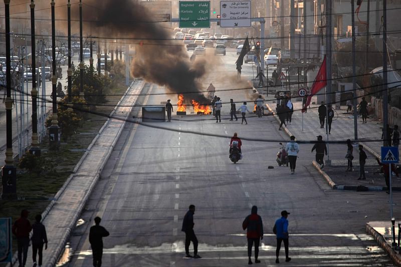 Iraqi demonstrators block a road with burning tyres as they protest the death of fellow protestors in clashes with security forces, in the southern city of Nasiriyah, on 11 December, 2022