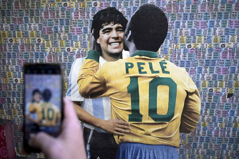 A man takes a picture of a wall depicting an image of late football stars Diego Maradona of Argentina and Pele of Brazil embracing each other, in Buenos Aires on 29 December, 2022, just hours after the passing of Pele