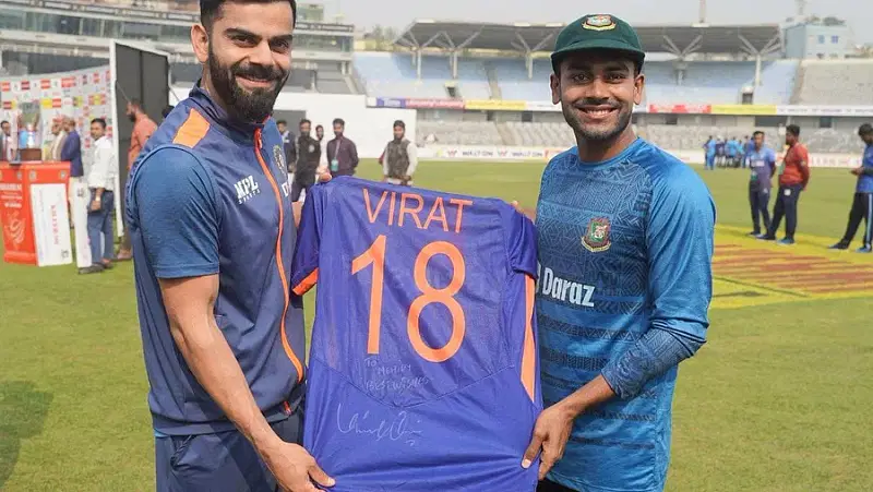 Virat Kohli and Mehidy Hasan Miraz pose with the signed jersey that Kohli gifted Miraz