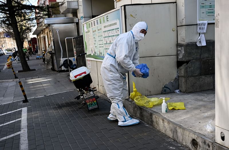 A worker wearing personal protective equipment (PPE) amid the Covid-19 pandemic is seen along a street in Beijing on 11 December, 2022.