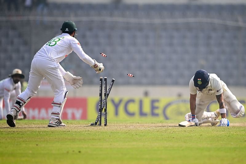 India’s Virat Kohli (R) dives to save his wicket as Bangladesh’s Nurul Hasan (C) tries to break the stumps during the second day of the second cricket Test match between Bangladesh and India at the Sher-e-Bangla National Cricket Stadium in Dhaka on 23 December, 2022